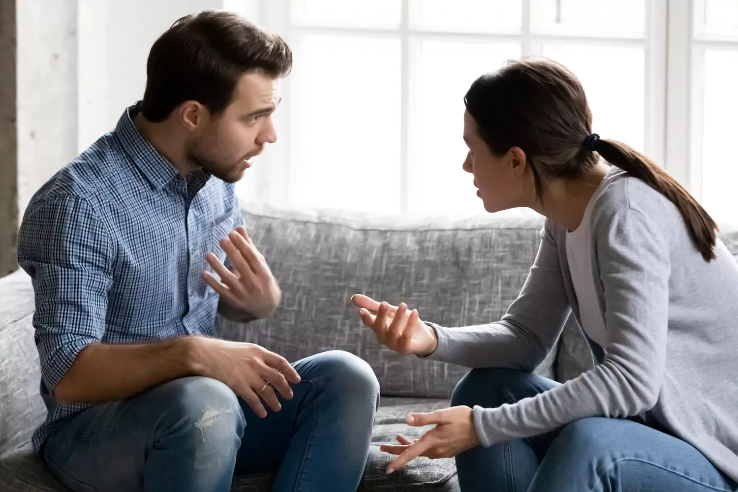 A married couple sitting together on a couch with a laptop and coffee, going through their accounts